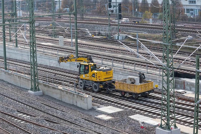 Yellow excavator next to railroad tracks on a large construction site in an urban environment, Untertürkheim parking lot, Stuttgart, Baden-Württemberg, Germany