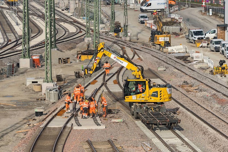 Rail construction with a group of workers and a yellow construction machine vehicle on the construction site, Untertürkheim parking station, Stuttgart, Baden-Württemberg, Germany