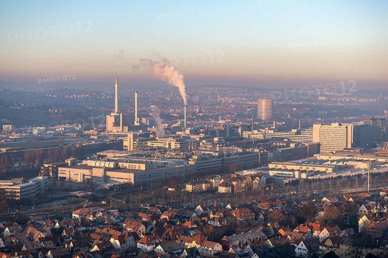 Aerial view of a city at dusk, with industrial structures and suburban houses, sky and smoke visible, view of Daimler Group headquarters, Untertürkheim plant, Stuttgart, Baden-Württemberg, Germany