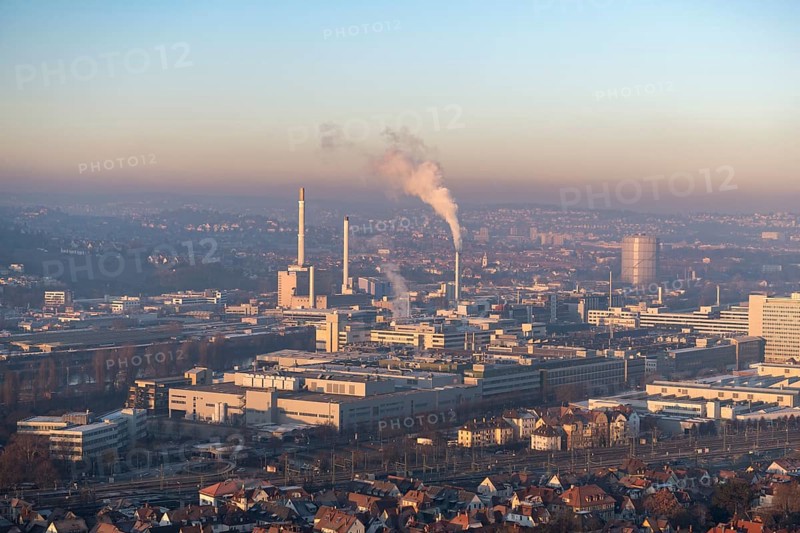 City view at dusk, modern buildings in the foreground, chimneys with smoke and a calm atmosphere in the sky, view of Daimler headquarters, Untertürkheim plant, Stuttgart, Baden-Württemberg, Germany