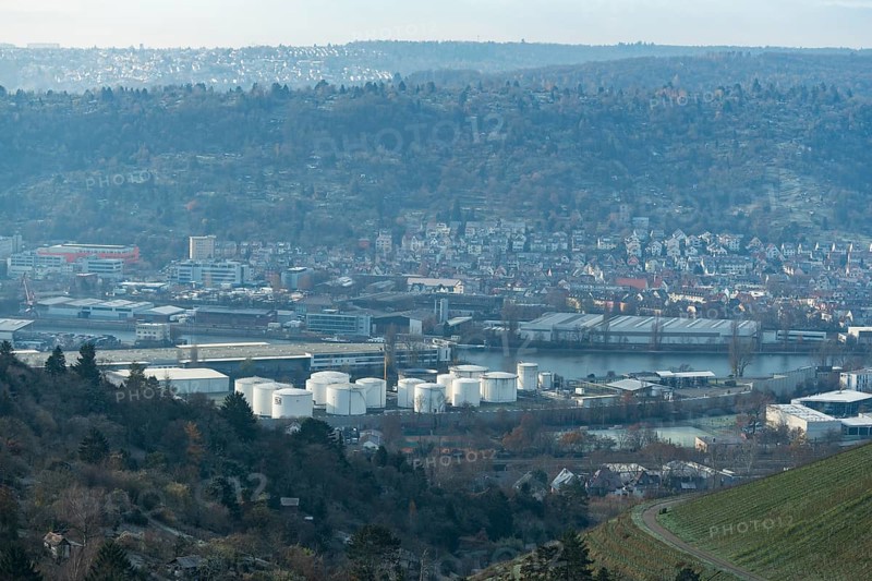 Industrial plant with white tanks in front of a hilly landscape covered with houses, view of harbour, Untertürkheim, Stuttgart, Baden-Württemberg, Germany