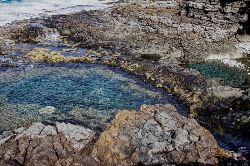 Rocky coast with cave and clear water. Waves and erosion shape the dark rock formations, Yaiza Lanzarote