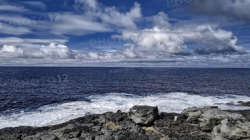 Rough sea under cloudy sky meets rocky coast. Atmospheric and wild with moving waves, Yaiza Lanzarote