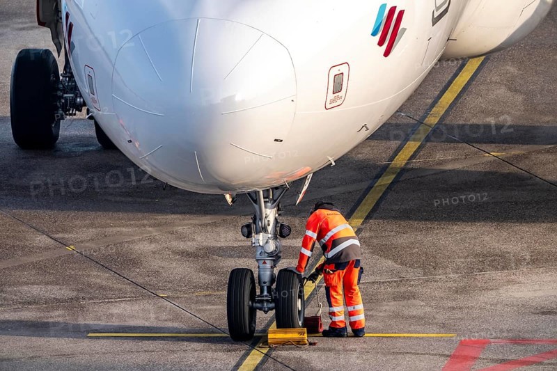 Ground crew positions brake blocks on the chassis, after stopping at the parking position, at the terminal, gate, at the Cologne/Bonn airport passenger bridge, CGN, North Rhine-Westphalia, Germany