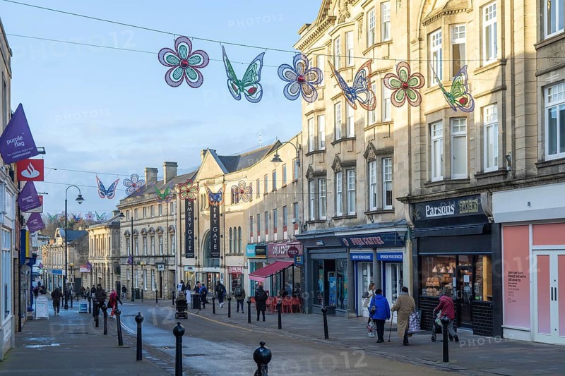 Christmas street decorations hang above quiet shopping street in January, town centre of Chippenham, Wiltshire, England, UK