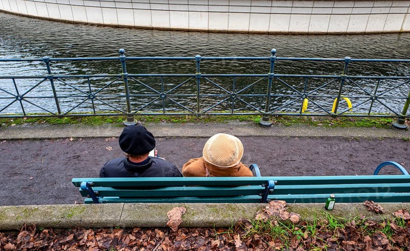 Senior couple sitting on a park bench at the Tegel harbor basin, Berlin, Germany