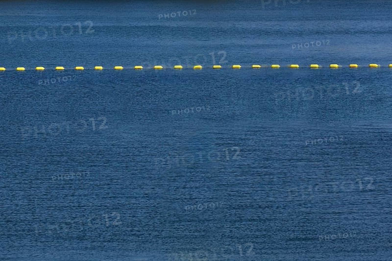 String of yellow cautionary navigation marker buoys on water surafce of river serving to warn, signal or indicate of a hazard beyond, Old Port of Montreal, Quebec, Canada