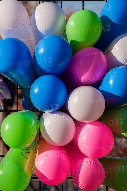 Close-up of colourful balloons inflated with helium gas and attached to black metal lattice support at amusement theme park in autumn, Quebec, Canada