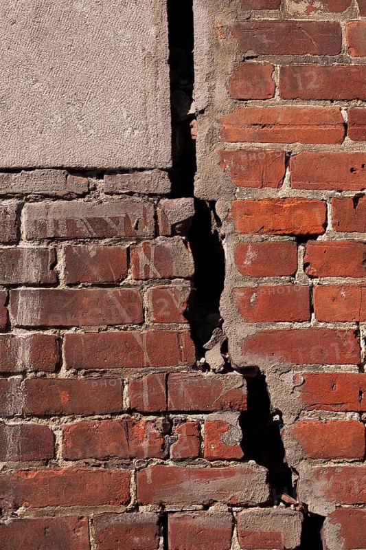 Close-up of large and deep wide open crack on exterior wall of red brick building, Quebec, Canada