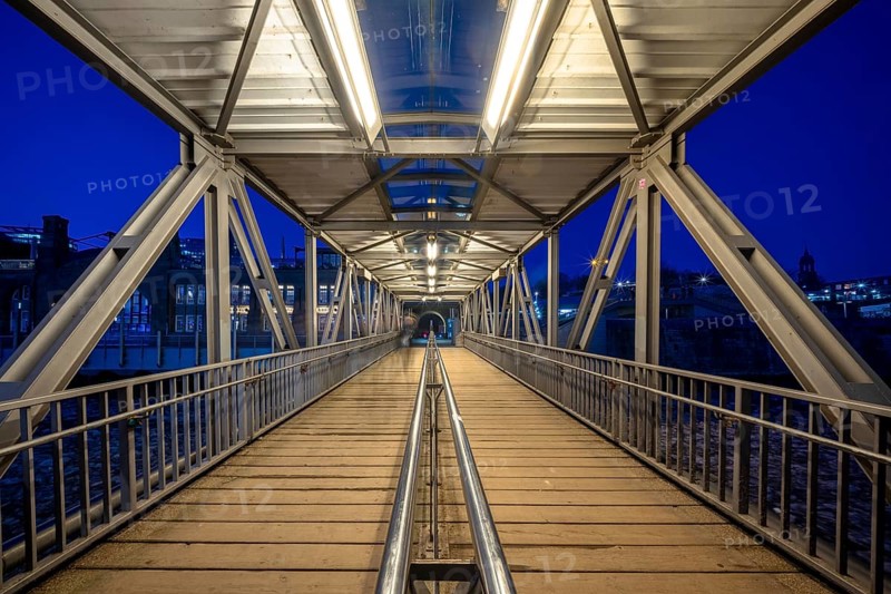 Illuminated pedestrian access jetty (bridge) to the Hamburg Landungsbrücken and jetty at night, Hamburg, Germany