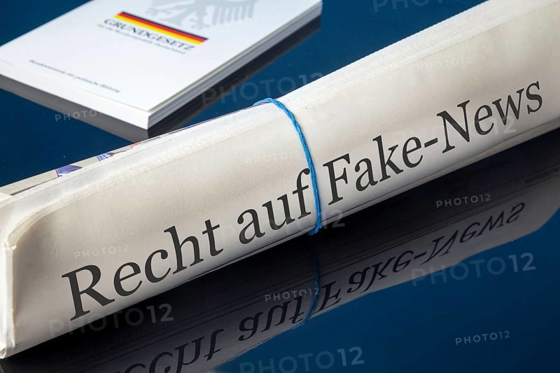 Symbolic newspaper with the headline RIGHT TO FAKE NEWS, with the German constitution in the background