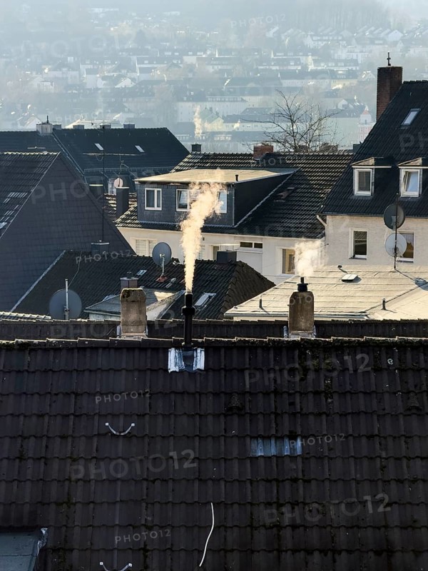 Smoke plume from a chimney over densely built residential area in the evening light, wintry city scene, Wuppertal, Germany