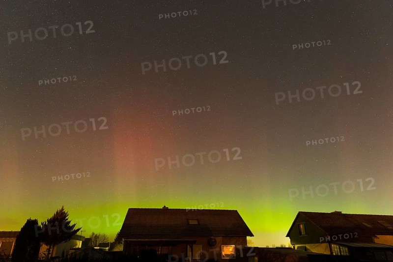 Shimmering red and green auroras over houses under clear starry skies, aurora borealis, Ilsede, Lower Saxony, Germany