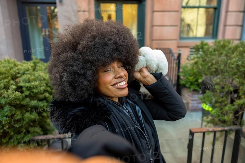 Young black woman with a big afro hairstyle taking a selfie, enjoying a sunny winter day in manhattan and showing natural beauty and happiness in an urban environment