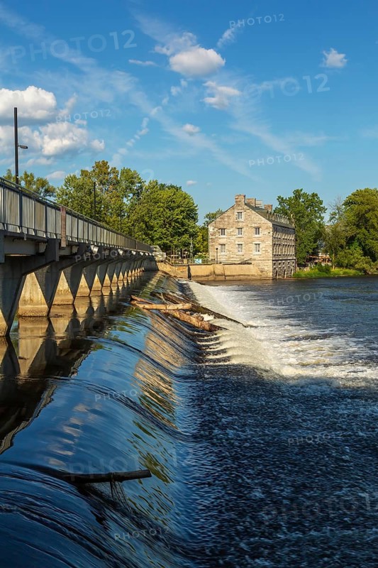 Moulin Neuf water flow control dam and walkway over Des Mille-Iles river plus New Mill on Ile des Moulins in summer, Old Terrebonne, Quebec, Canada