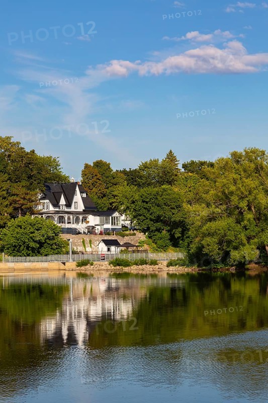 19th century multistory old white clapboard home with black rooftops and backyard built on edge of Des Mille-Iles River in summer, Terrebonne, Quebec, Canada