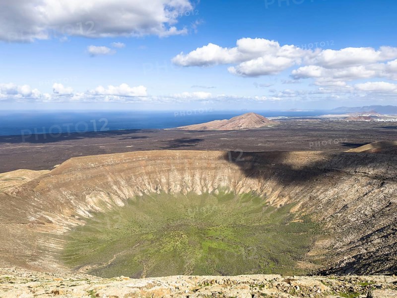 View of the Caldera Blanca volcano cauldron against blue sky with white clouds, Mancha Blanca, Lanzarote, Canary Islands, Spain
