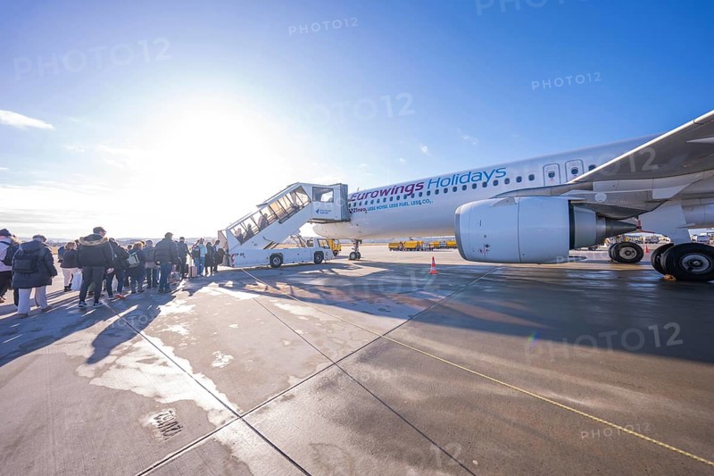 Passengers board an airplane via a mobile staircase under bright blue skies, Stuttgart Airport, Germany