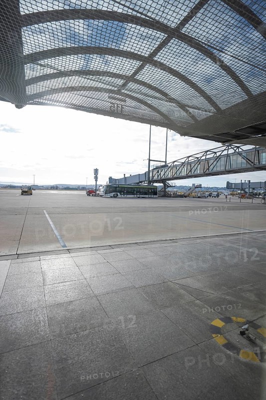 View of the apron of an airport with a bus and a mesh roof in bright sunlight, Stuttgart Airport, Germany