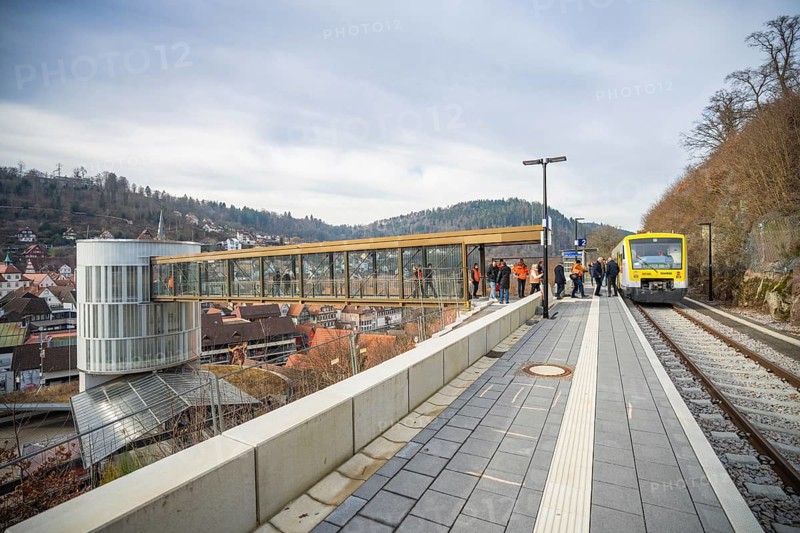 A train approaches a station with a wide panorama and hills in the background, taking off the Hermann Hessebahn, Calw, Germany