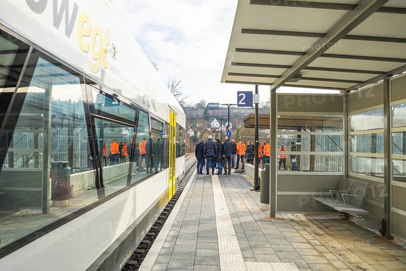 People standing in a group on a platform next to a train at a bus stop, the Hermann Hessebahn ride, Calw, Germany