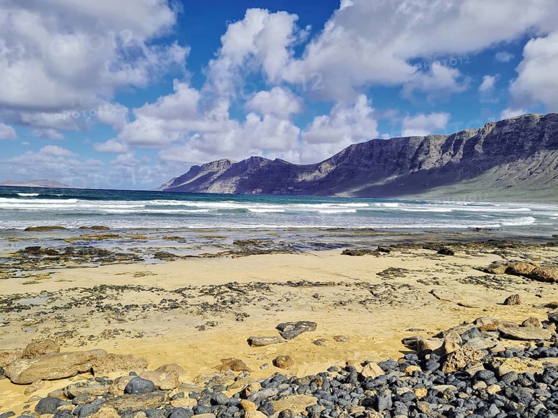 Wide beach with rocky coast and mountains in the background, Caleta de Famara Lanzarote