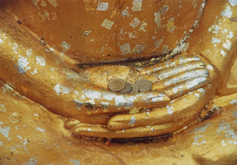 Donations for the temple in the hands of a Buddha sculpture. Buddha, Buddhism, religion, Bangkok, Thailand, Southeast Asia