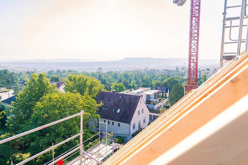 A view from a roof shows a landscape with trees and a crane in the background, carpentry, new building, Stuttgart, Germany