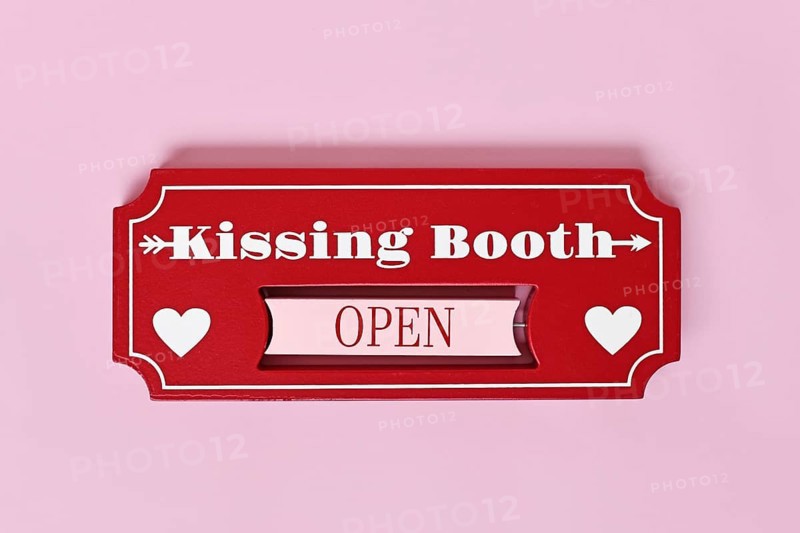 Valentine's Day kissing booth sign with hearts on pink background. Romantic love concept flat lay