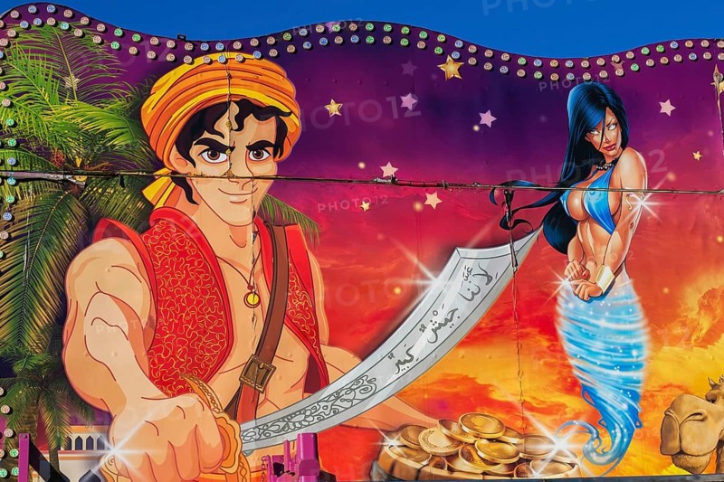 Painted illustration of Aladin brandishing a sword and a voluptuous blue eyed genie on amusement ride at Fun Show traveling amusement ride park, Old Port of Montreal, Quebec, Canada