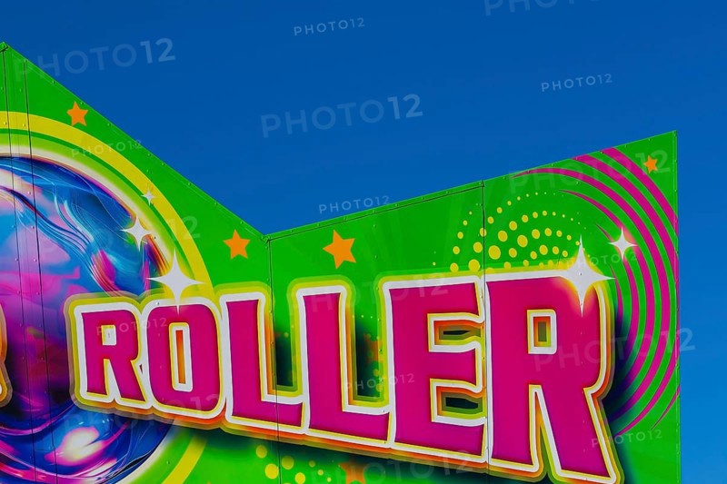 Close-up of the word Roller painted in purple fluorescent paint on banner at Fun Show traveling amusement ride park, Old Port of Montreal, Quebec, Canada