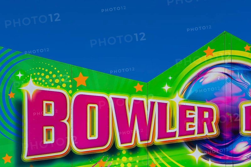 Close-up of the word Bowler painted in purple fluorescent paint on banner at Fun Show traveling amusement ride park, Old Port of Montreal, Quebec, Canada