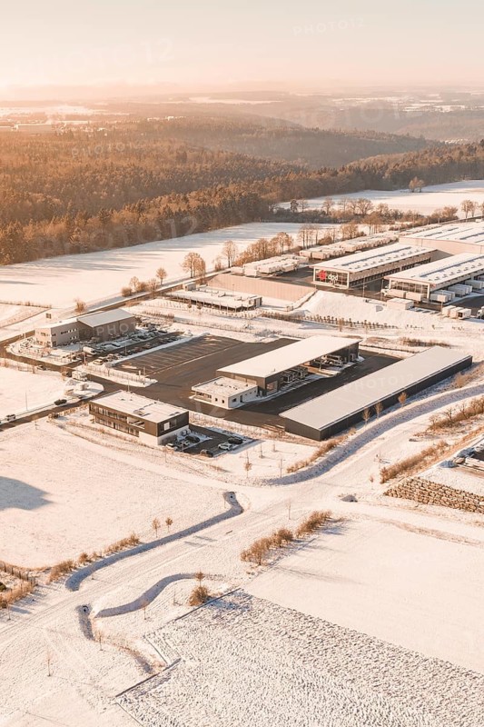 Snowy industrial landscape at sunset surrounded by fields and trees, Nagold, Calw district, Black Forest, Germany