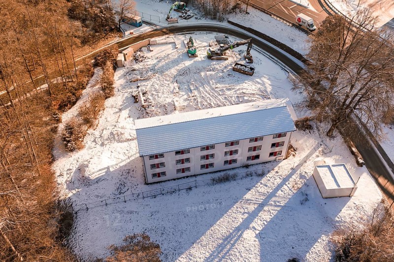 Building on construction site in the forest, surrounded by snow and cranes in a wintry atmosphere, Nagold, Calw district, Black Forest, Germany