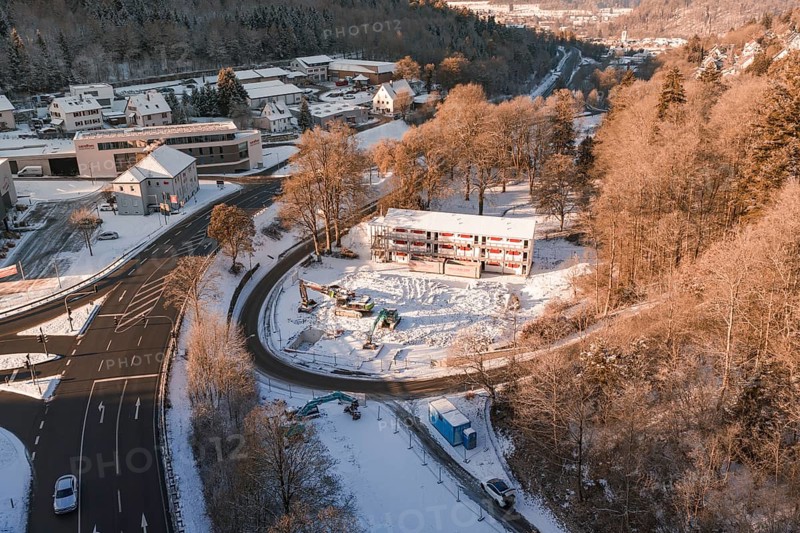 Snow-covered construction site and roads with a view of a wintry settlement and forest, Nagold, Calw district, Black Forest, Germany