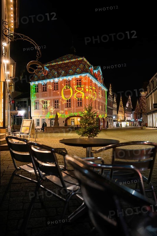 Evening scene with illuminated historic building and empty café chairs in the foreground, Nagold, Calw district, Black Forest, Germany
