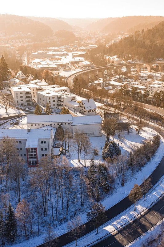 Residential building in a snowy urban landscape with roads and a bridge, surrounded by hills, Nagold, Calw district, Black Forest, Germany