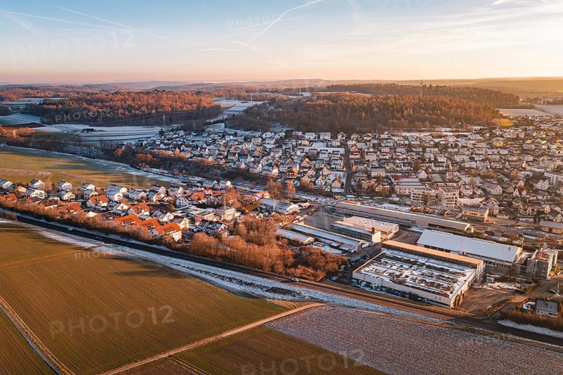 Aerial view of a settlement in winter surrounded by fields and roads, under blue sky, Althengstett, Calw district, Germany