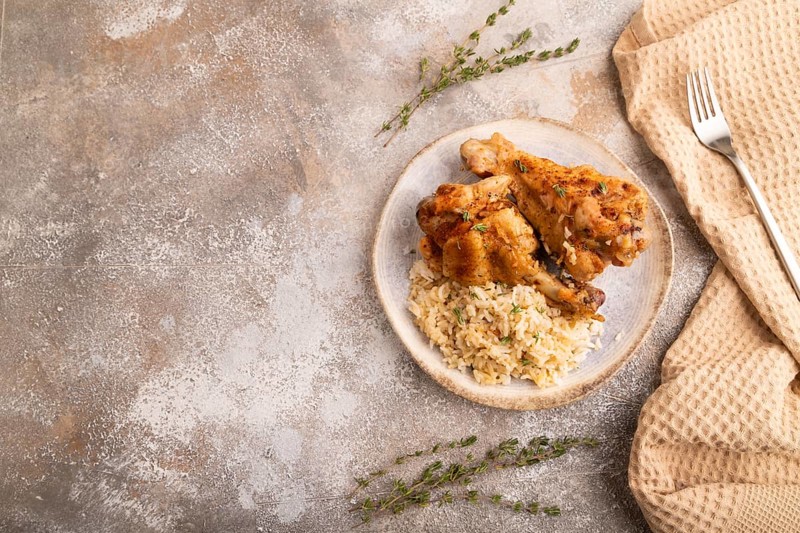 Fried Turkey Wing with spices and rice on brown concrete background and linen textile. top view, flat lay, copy space