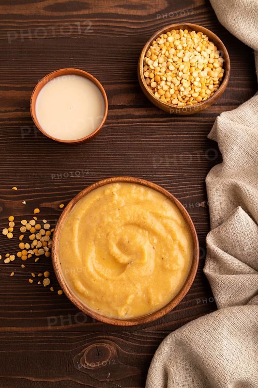 Pea cream soup, Puree, porridge in wooden bowl on wooden background and linen textile. Diet, healthy eating concept. top view, flat lay, close up, minimalism