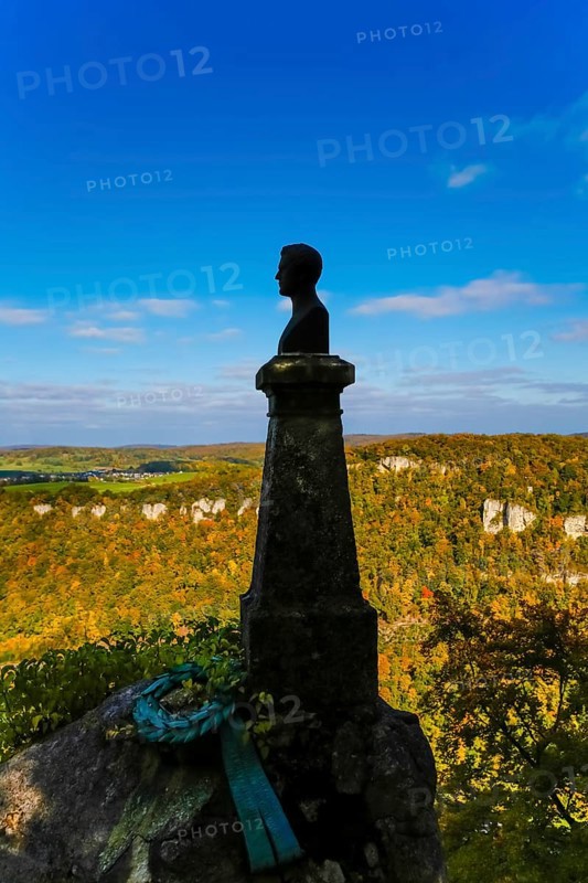 Wilhelm Hauff memorial, rocks above the Echaz Valley, monument from 1839, obelisk with bronze bust, viewpoint, historical monument, south of Lichtenstein Castle, at the eave of the Swabian Jura, view, blue sky, Honau, municipality of Lichtenstein, Baden-Württemberg, Germany