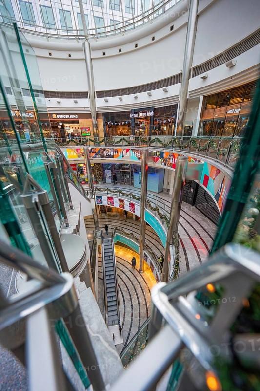 Multi-storey shopping center with escalators and shops behind glass fronts, London, England, United Kingdom
