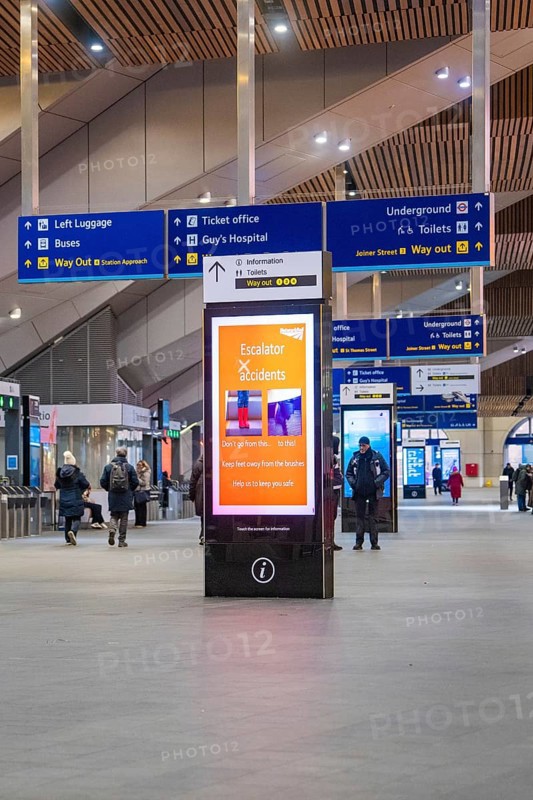 Lively train station with signs and people, modern decor and displays, London, England, Great Britain