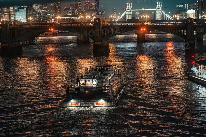 Boat under an illuminated bridge on a river at night, city lights reflecting in water, London, England, Great Britain