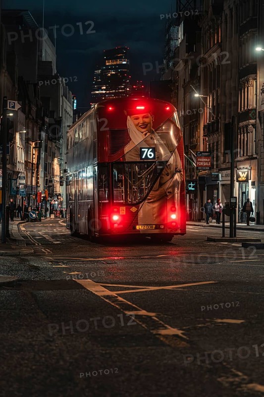 Double-decker bus travels at night through an illuminated city street surrounded by buildings, London, England, Great Britain