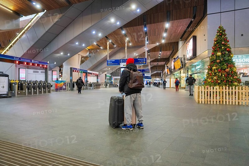 A traveler in a train station with luggage surrounded by modern architecture and Christmas decoration, London, England, Great Britain