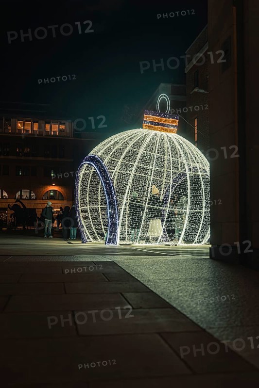 Large glowing Christmas ball on square with people in the evening setting, London, England, Great Britain