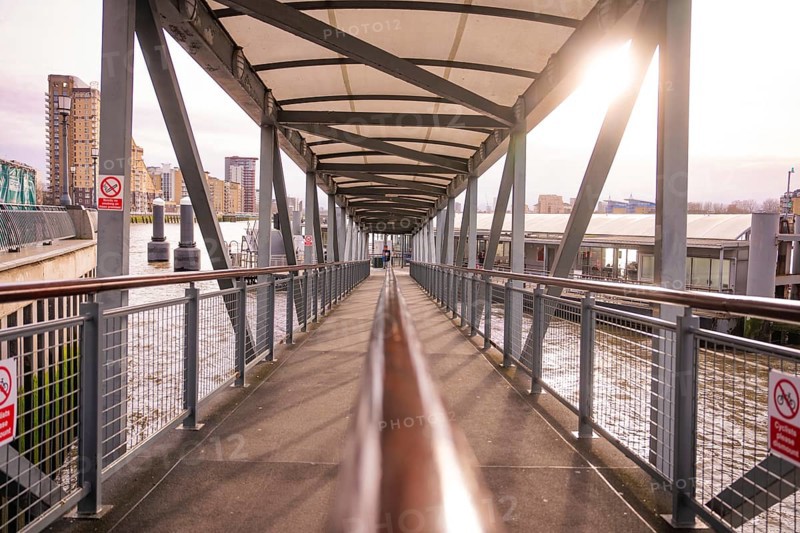 A modern steel bridge with a roof in an urban area, facing the sun, London, England, Great Britain
