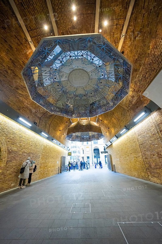 An artistically designed brick vault with lettering and people in an urban space, London Bridge Station, London, United Kingdom