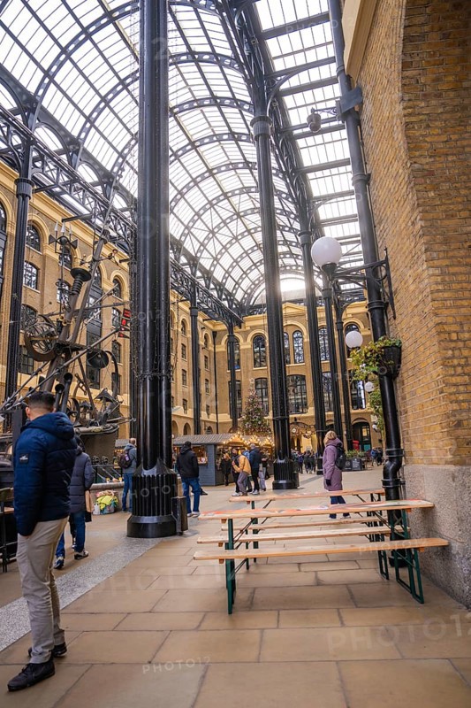 Interior with beer benches and people surrounded by vaulted brick walls and a glass roof, London, United Kingdom